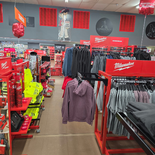 A store aisle filled with red Milwaukee tool boxes, bags, tools and storage units. Bright lighting reflects off the red decor, creating a vibrant, energetic atmosphere.