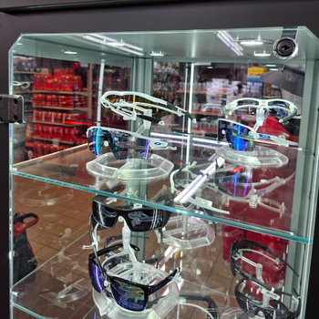Display case showcasing various sports sunglasses with colorful reflective lenses. The background shows a store interior with bright lighting.