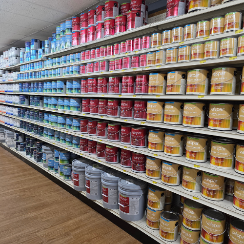 Shelves in a store display an array of paint cans organized by color: blue, red, and beige. The neatly arranged rows create a vibrant, orderly scene.