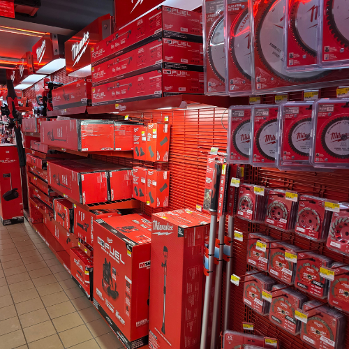 A store aisle filled with red Milwaukee tool boxes, bags, tools and storage units. Bright lighting reflects off the red decor, creating a vibrant, energetic atmosphere.
