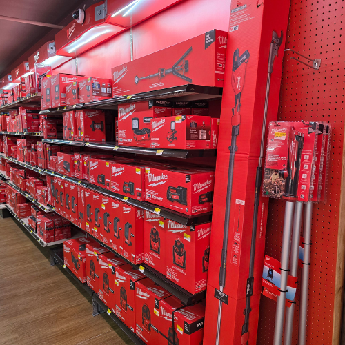 A store aisle filled with red Milwaukee tool boxes, bags, tools and storage units. Bright lighting reflects off the red decor, creating a vibrant, energetic atmosphere.