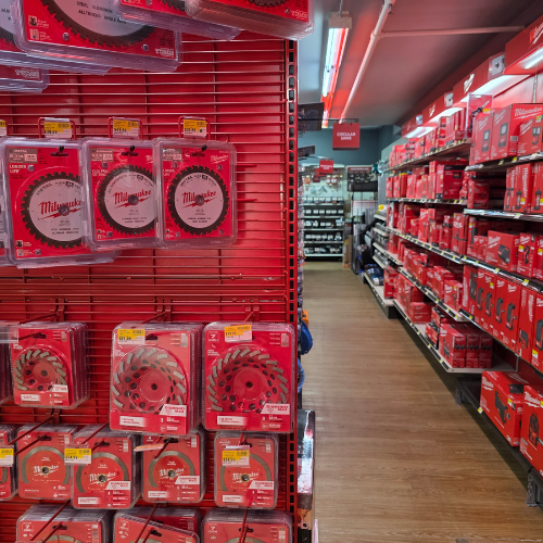 A store aisle filled with red Milwaukee tool boxes, bags, tools and storage units. Bright lighting reflects off the red decor, creating a vibrant, energetic atmosphere.