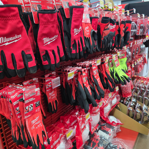 A store aisle filled with red Milwaukee tool boxes, bags, tools and storage units. Bright lighting reflects off the red decor, creating a vibrant, energetic atmosphere.