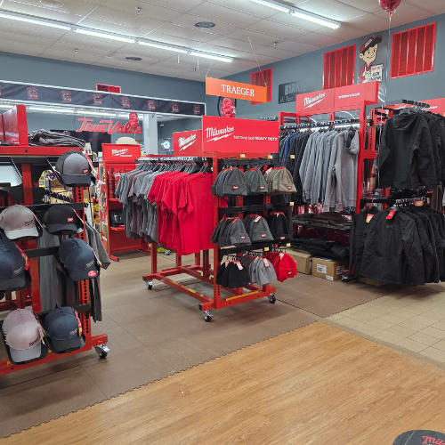 A store aisle filled with red Milwaukee tool boxes, bags, tools and storage units. Bright lighting reflects off the red decor, creating a vibrant, energetic atmosphere.