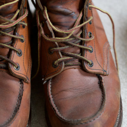 Footwear & ApparelClose-up of worn brown leather boots with intricate laces, showing scuffs and creases, conveying a rugged, vintage feel.